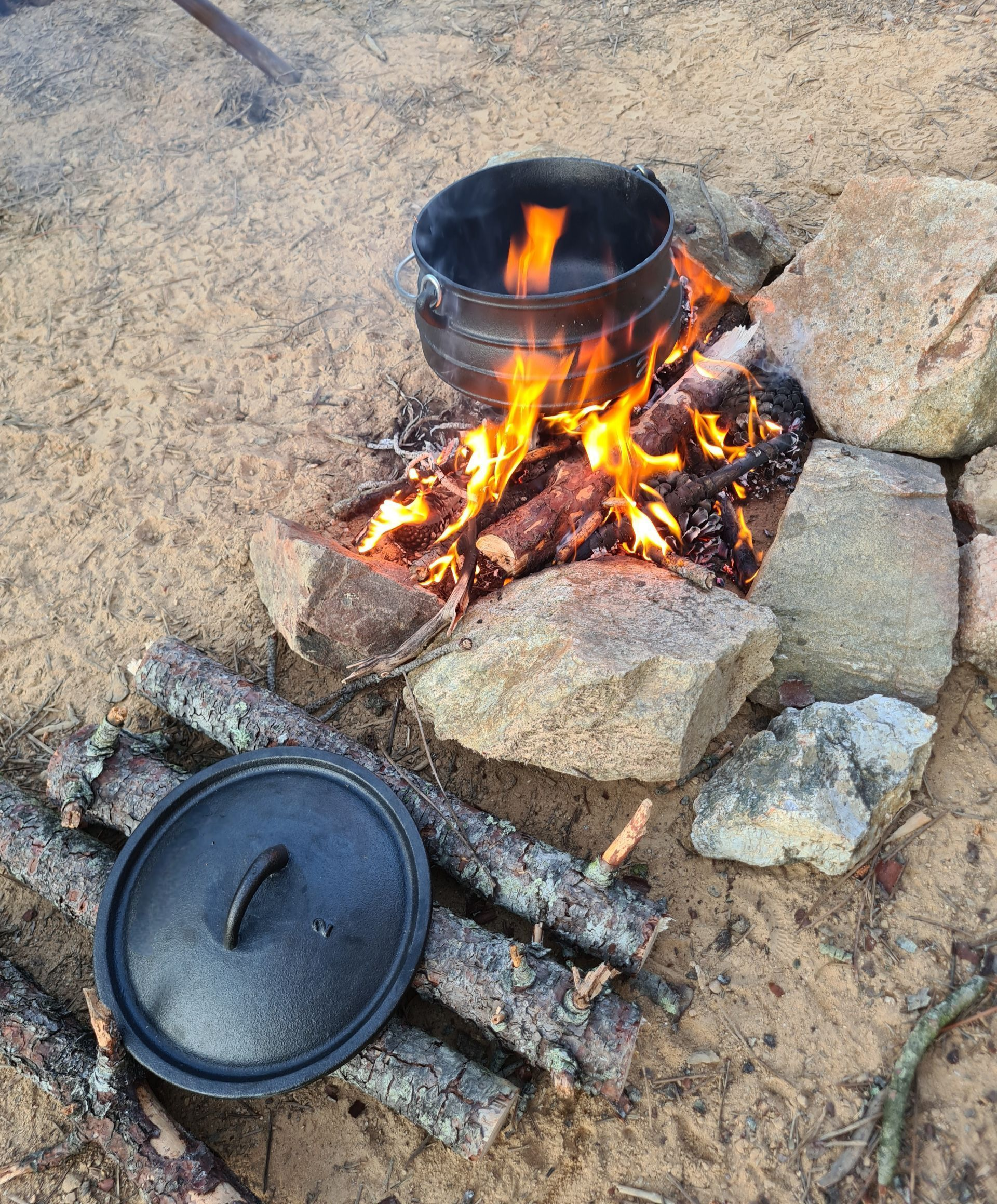Chaudron sur un feu de bois qui évoque la cuisine outdoor en liberté.