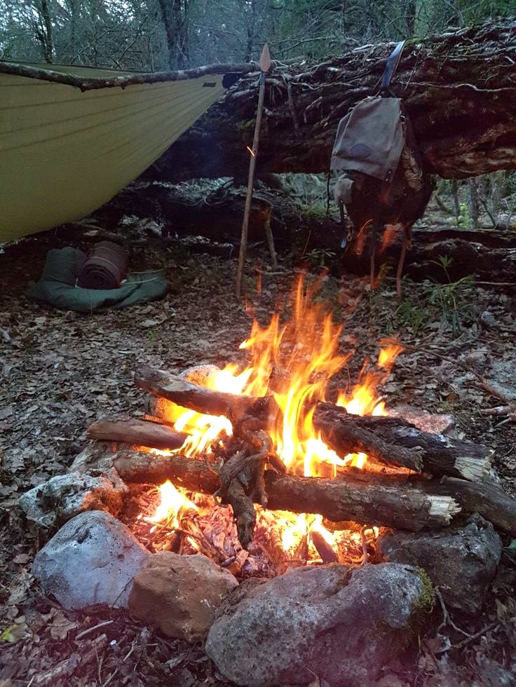 Feu de bois dans la nature devant un bivouac.