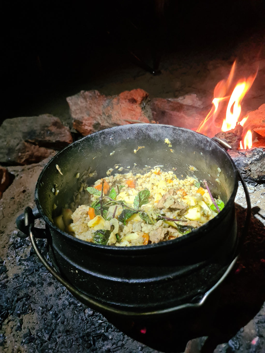 Chaudron contenant de la nourriture cuite au feu de bois.