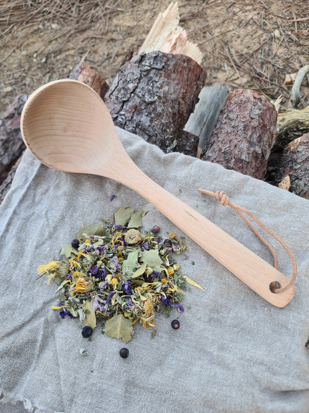 Louche en bois de hêtre posée à côté d'aromates des Gaules.
